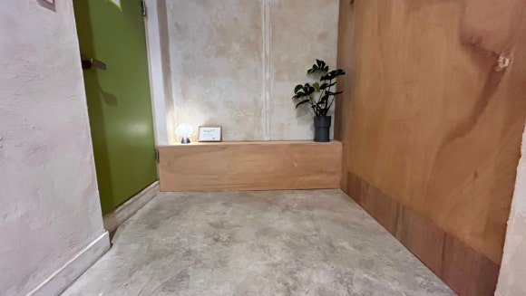 화장실 앞에서 기다릴 때 앉을 수 있도록 벽 하단에 제작한 작은 합판 붙박이 의자가 통로 안쪽에 설치된 모습.