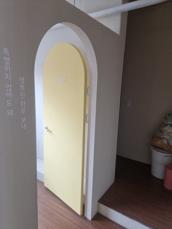 "부드러운 시각적 개방감을 선사하는 아치형 게이트틀 모습, MDF와 석고보드를 곡선 벤딩 가공하여 도장 마감이 단차 없이 깔끔하게 연출된 정밀 아치 게이트와 옐로우 도어의 조화"