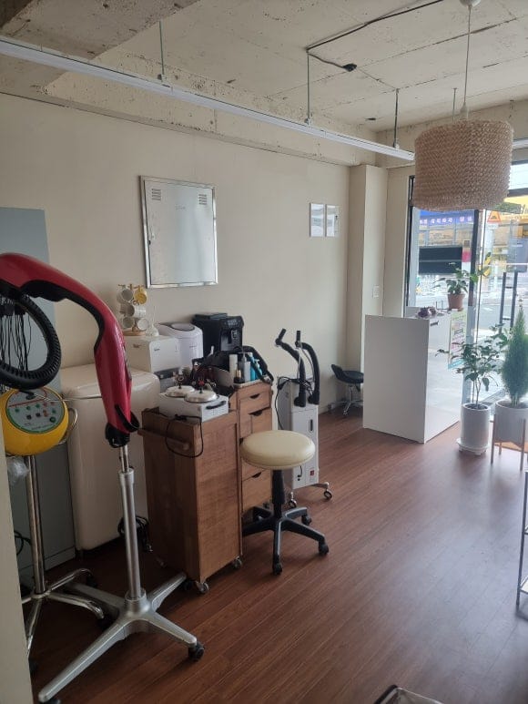 "미용실 내부의 중앙 시술 구역, 정교한 벽면 목공 작업을 거쳐 군더더기 없이 일직선으로 떨어지는 벽면 라인과 모던한 시술 장비들이 어우러진 마감 모습"
