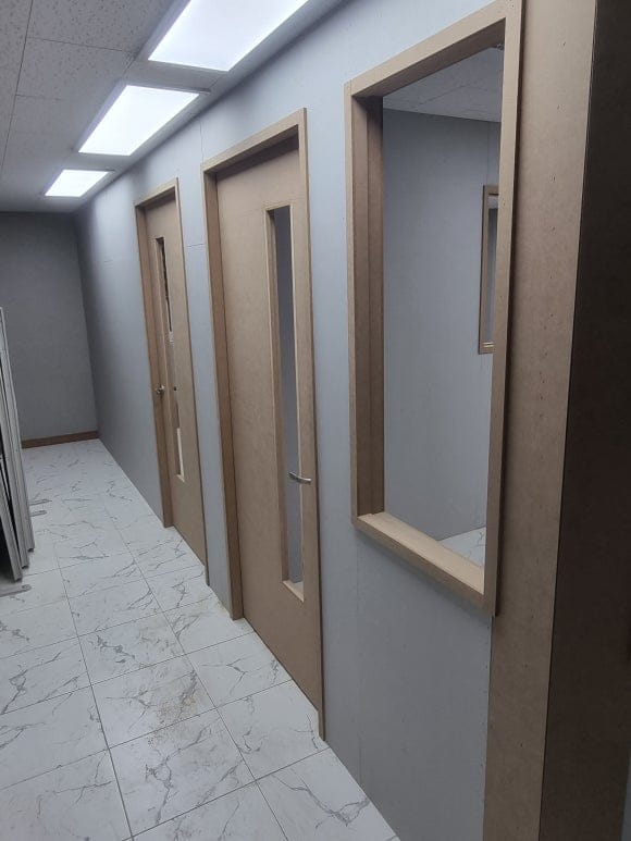 목공 작업을 마친 뒤 다른 공정이 들어오기 전의 학원 복도로, 강의실 문틀과 통창 테두리의 MDF가 노출된 상태.