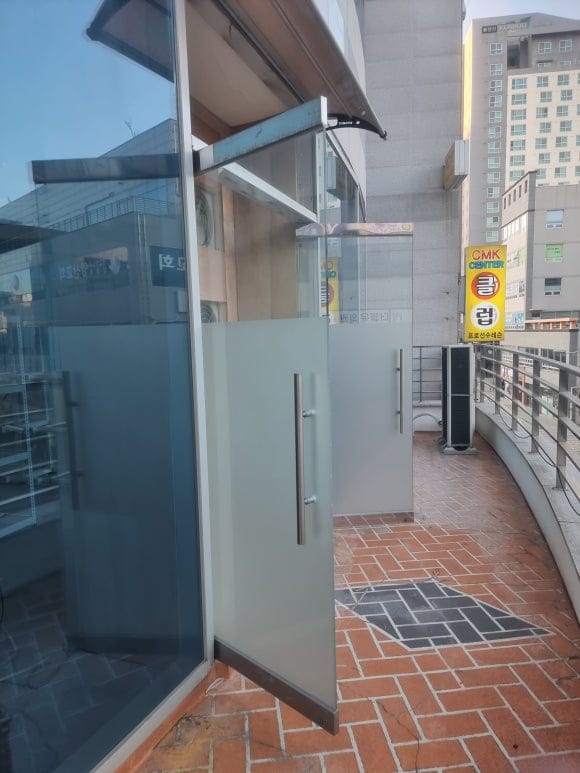 베란다 외부에서 촬영한 배기 구조물로, 원활한 공기 배출을 위해 문 위 유리 한 장을 떼어내고 하부에는 빗물이 밖으로 흐르도록 경사를 준 모습.
