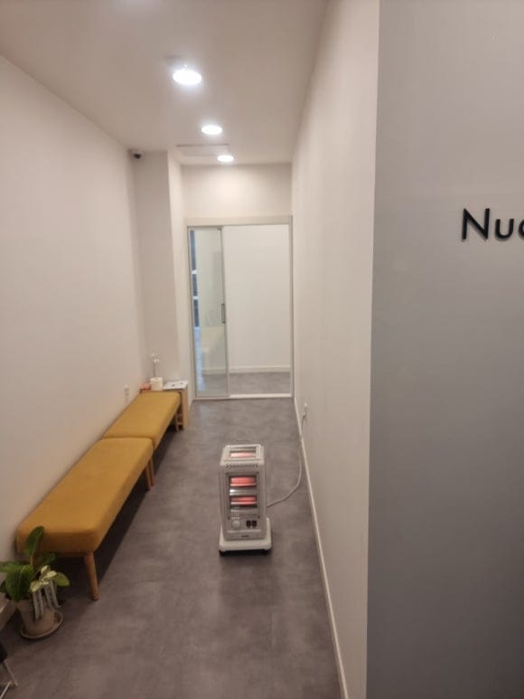 학원 메인 출입복도로, 입구에서 안쪽 홀 방향까지 긴 동선이 이어지고 천장 조명이 일렬로 설치된 모습.