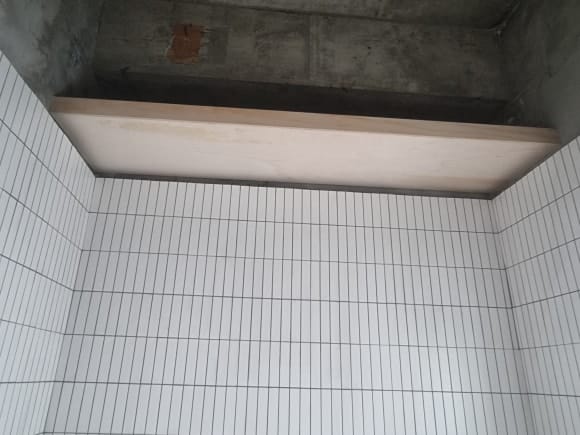 화장실 상부 벽면 폭에 맞춰 휴지와 비품을 보관할 수 있도록 제작한 대형 합판 선반의 목공 완료 모습.