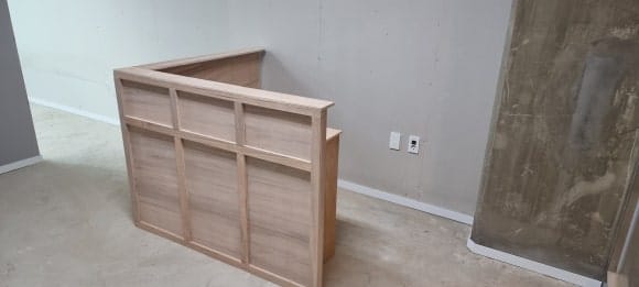 입구 쪽에서 바라본 마감 전 카운터로, 바깥 면의 십자가 무늬와 공간 전체에 시공한 흰색 걸레받이가 보이는 모습.
