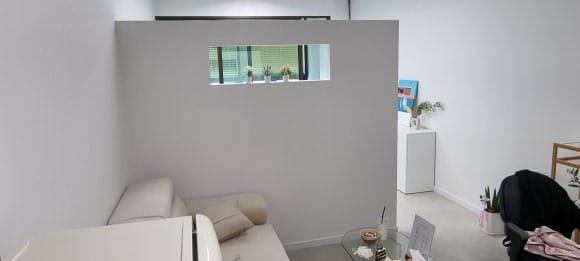 가게 입구에서 바라봤을 때 시술 침대가 직접 보이지 않도록 파티션 벽으로 공간을 가린 내부 전경.