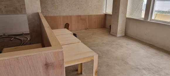 홀 안쪽 벽을 따라 설치한 수도 배관 가림 구조물과 직접 제작한 테이블을 함께 촬영한 목공 작업 후 모습.