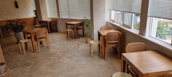 카페 안쪽 홀에 직접 제작한 소형 합판 테이블과 기성품 의자들이 여러 방향으로 배치된 전체 모습.