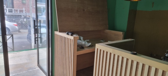 사진 15. 입구 쪽에서 바라본 주방 공간으로, 세로 목재로 마감한 파티션과 포스장 구조가 도장 전 상태로 설치되어 있습니다.