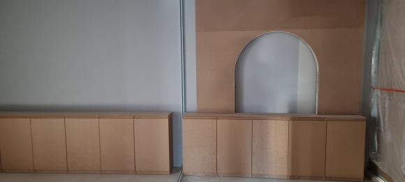 사진 23. 다른 마감 공정이 들어오기 전 대기실 벽면과 맞춤 하부장의 목공 상태로, 중앙에는 아치형 포인트 공간이 마련되어 있습니다.