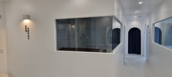 사진 2. 입구 오른편에 강의실 네 곳이 이어진 복도로, 모서리가 열린 통창과 복도 끝 창고 앞 아치형 게이트가 함께 보입니다.