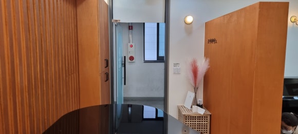 사진 4. 입구 통로에서 바라본 피아노 뒤 나무 장식벽과 공간을 구분하는 벽 역할을 함께 수행하는 책꽂이 장.