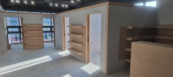 사진 18. 복도 홀에서 바라본 목공 완료 상태로, 벽면의 여러 단 진열 선반과 출입구 주변 구조가 함께 보입니다.