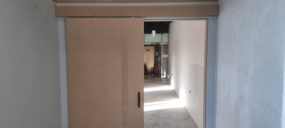 사진 21. 복도 끝에서 바라본 목공 완료 상태로, 슬라이딩 도어와 상부 레일 가림 구조가 출입구에 맞춰 제작되어 있습니다.