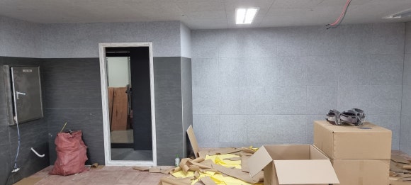 사진 42. 차음판 시공이 끝난 벽면 위로 회색 아트보드를 붙이는 과정으로, 터닝도어 주변까지 마감이 이어진 상태.