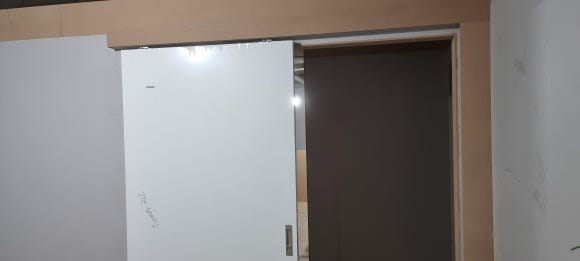 사진 34. 복도 안쪽에서 바라본 슬라이딩 도어 시공 구간으로, 여러 태닝룸 출입문과 상부 레일 가림 구조가 이어지는 모습.