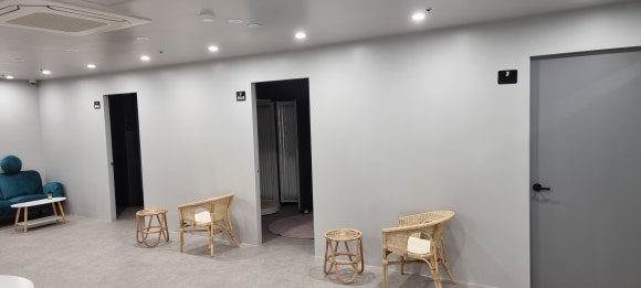 사진 3. 태닝샵 좌측 복도에 나란히 배치된 태닝룸 세 곳의 출입문과 도장 마감된 벽체가 보이는 모습입니다.