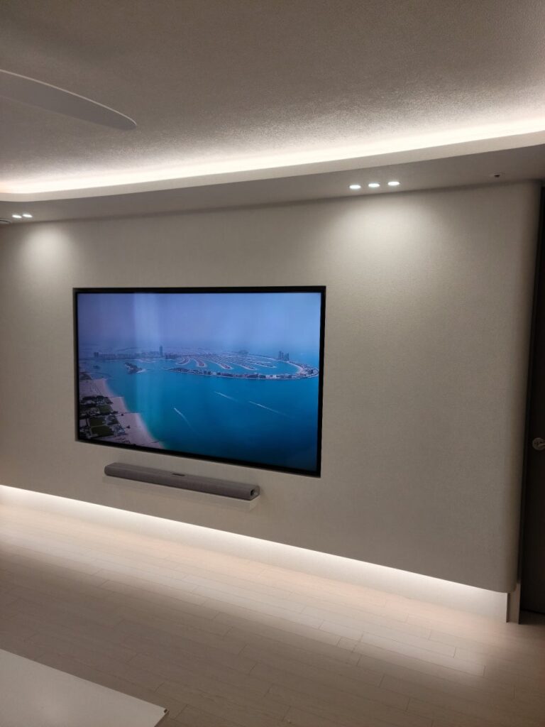 사진 6. 거실 측면에서 바라본 TV 반매립 벽체로, TV와 사운드바 아래쪽을 따라 간접조명이 켜진 모습.