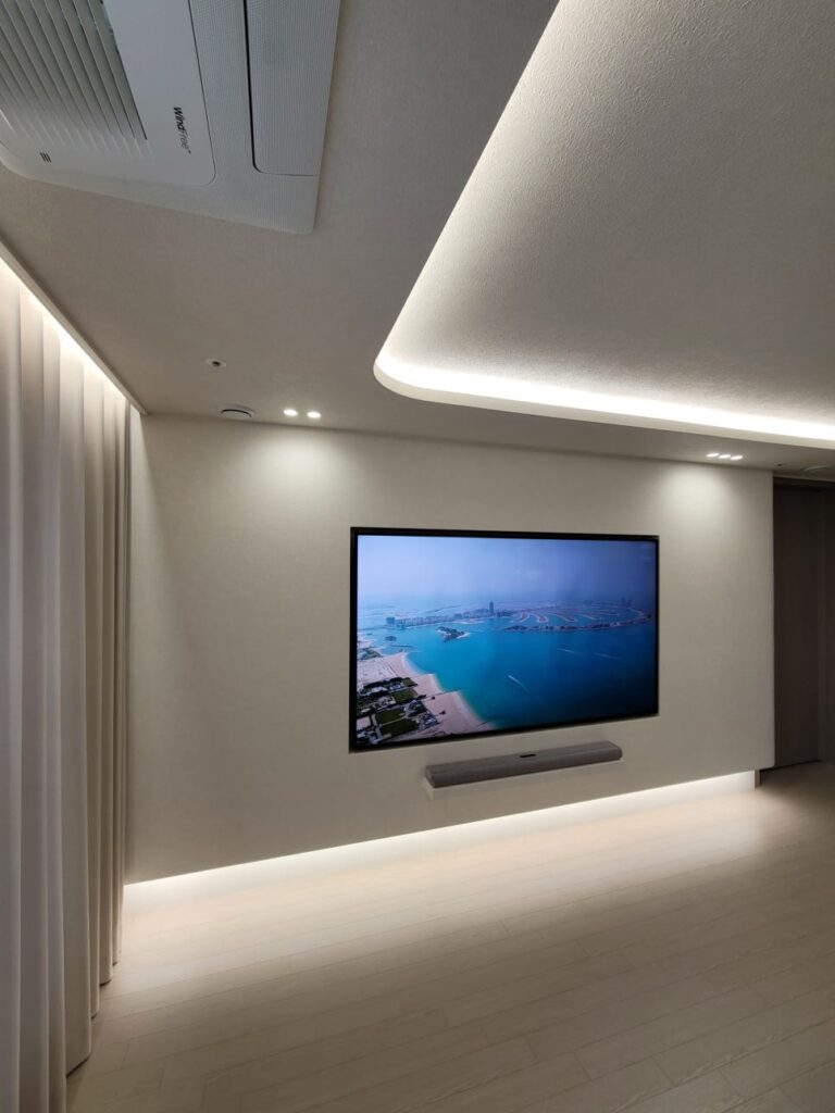 사진 5. 천장 조명과 TV 벽체 하부 간접조명을 켠 상태에서 바라본 TV 반매립 벽과 사운드바 선반의 정면 모습.