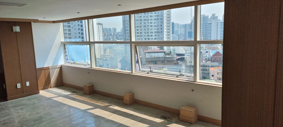 사진 4. 창가 벽체와 하부 가림 구조물이 길게 이어져 있으며, 바닥 쪽에는 기존 철제 골조를 가리는 사각형 함이 배치되어 있습니다.