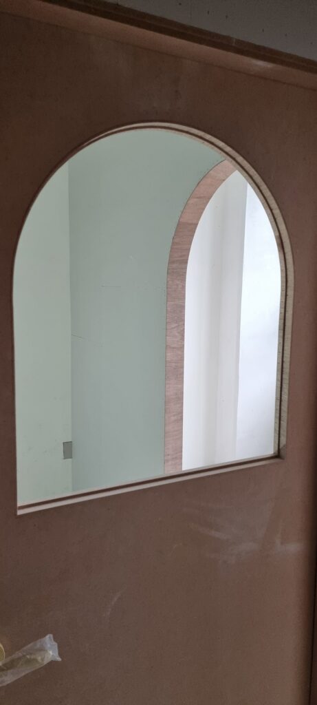 사진 31. 강의실 출입문을 가까이에서 촬영한 모습으로, 아치형 유리 자리를 낸 문짝과 곡선 테두리의 목작업 상태가 확인되는 모습.
