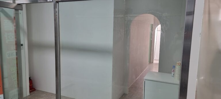 사진 2. 교습소 출입구를 비스듬한 각도에서 촬영한 모습으로, 유리 전면 너머로 아치형 통로와 정수기 설치 예정 수납장이 보이는 상태.