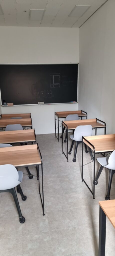 사진 12. 원장실 안에서 강의실을 바라본 모습으로, 칠판이 설치된 벽과 책상 및 의자가 배치된 강의 공간이 보이는 상태.