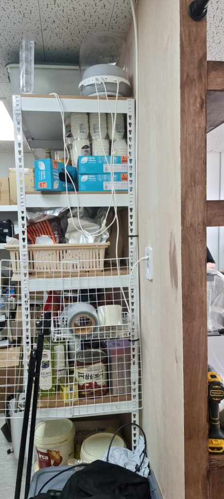 사진 10. 카운터 뒤쪽 벽체를 측면에서 촬영한 모습으로, 벽 뒤편으로 주방의 선반과 수납공간이 이어지는 구조가 보입니다.