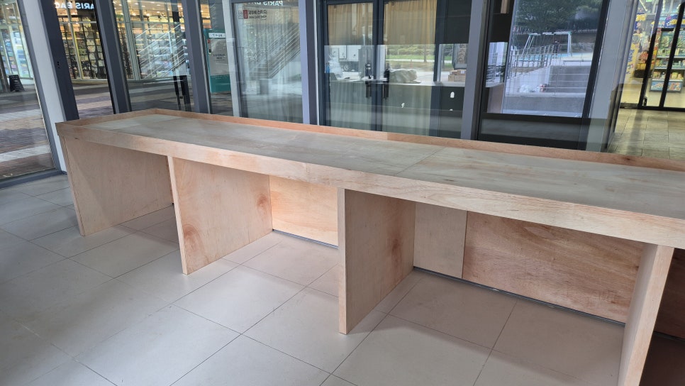 사진 22. 긴 매대의 제작이 진행된 모습으로 상판 아래에 여러 개의 칸이 나뉘어 있고, 각각의 매대가 독립된 형태로 제작되고 있습니다.